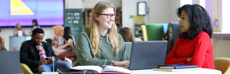 Two students work at a desk in the Leeds University Union