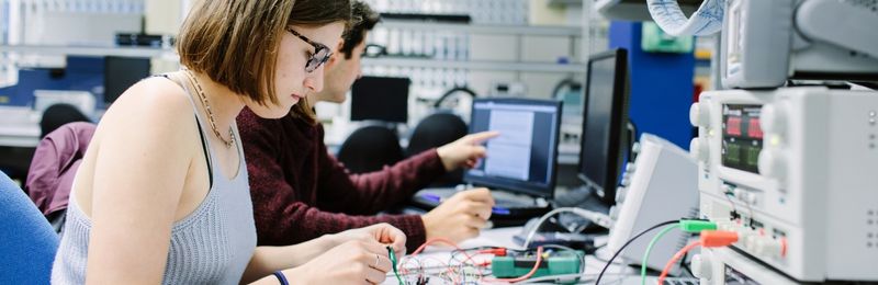 Two students working at a bench in the NXP lab in the School of Electronic and Electrical Engineering.