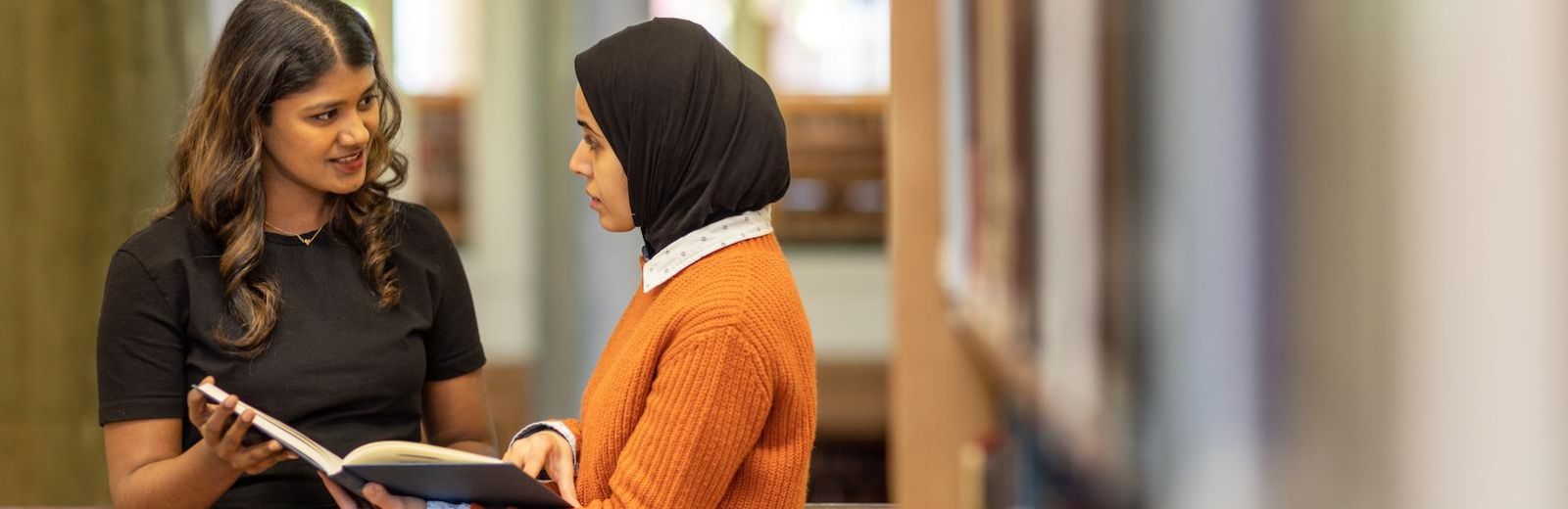 Two students looking at a book together on the balcony of the Brotherton Library.