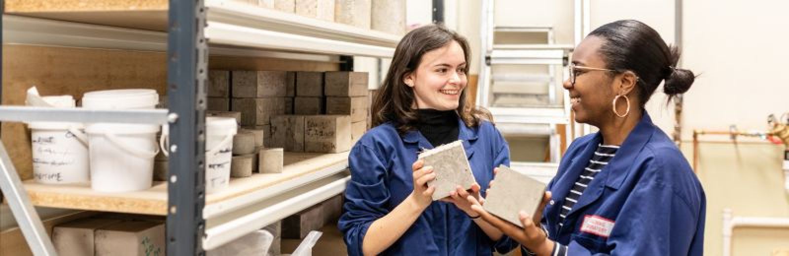 Image of two female students holding concrete in the civil engineering lab at the university of leeds.