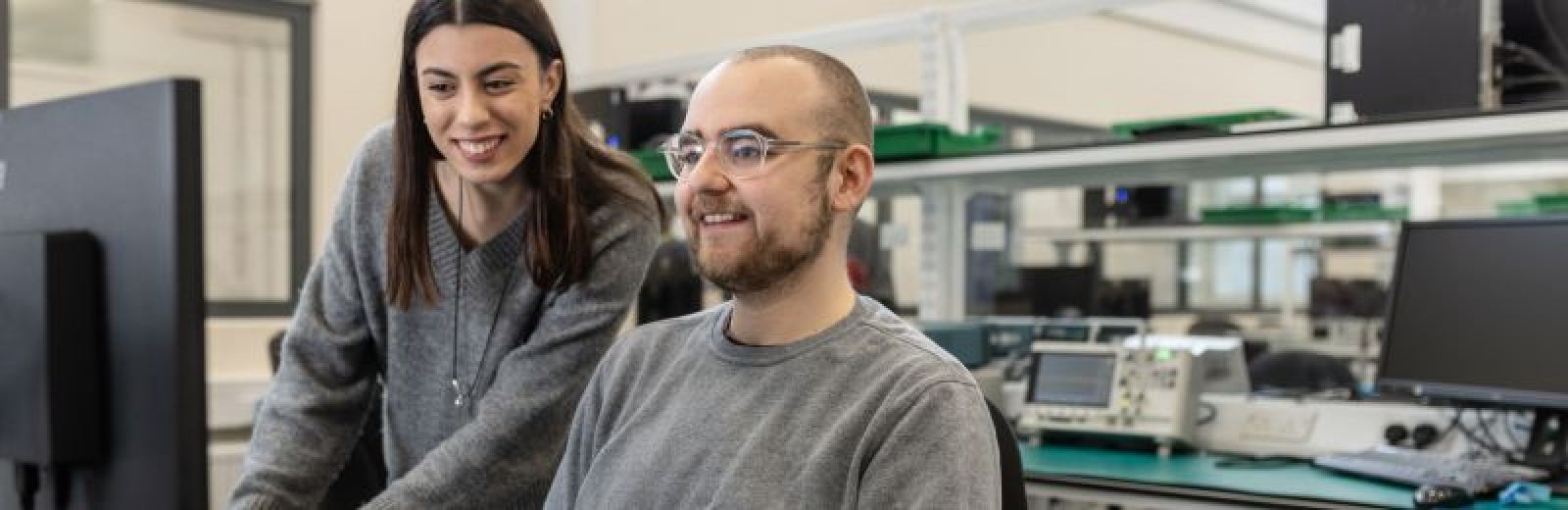 Two students sat at a workbench, working on a computer in the NXP Lab.