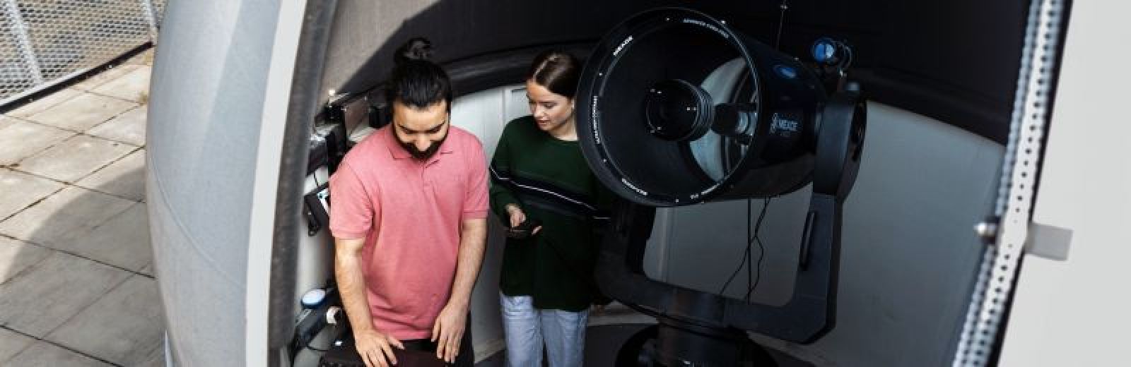 Two students working with a telescope at the University of Leeds.