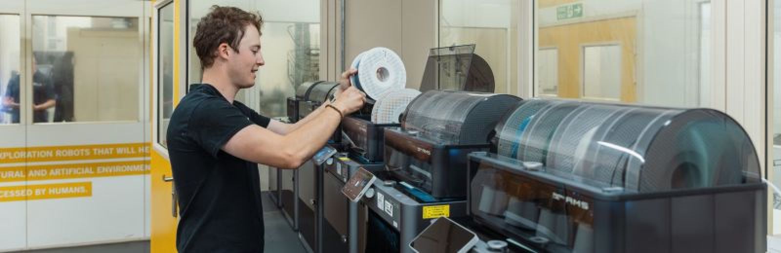 A student loading a new coil of material in to a 3D printer.