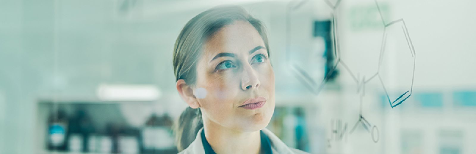 Female scientist using a digital tablet while looking at the Carbamazepine molecule writing on a glass screen in a laboratory, thinking whether to redesign the drug.