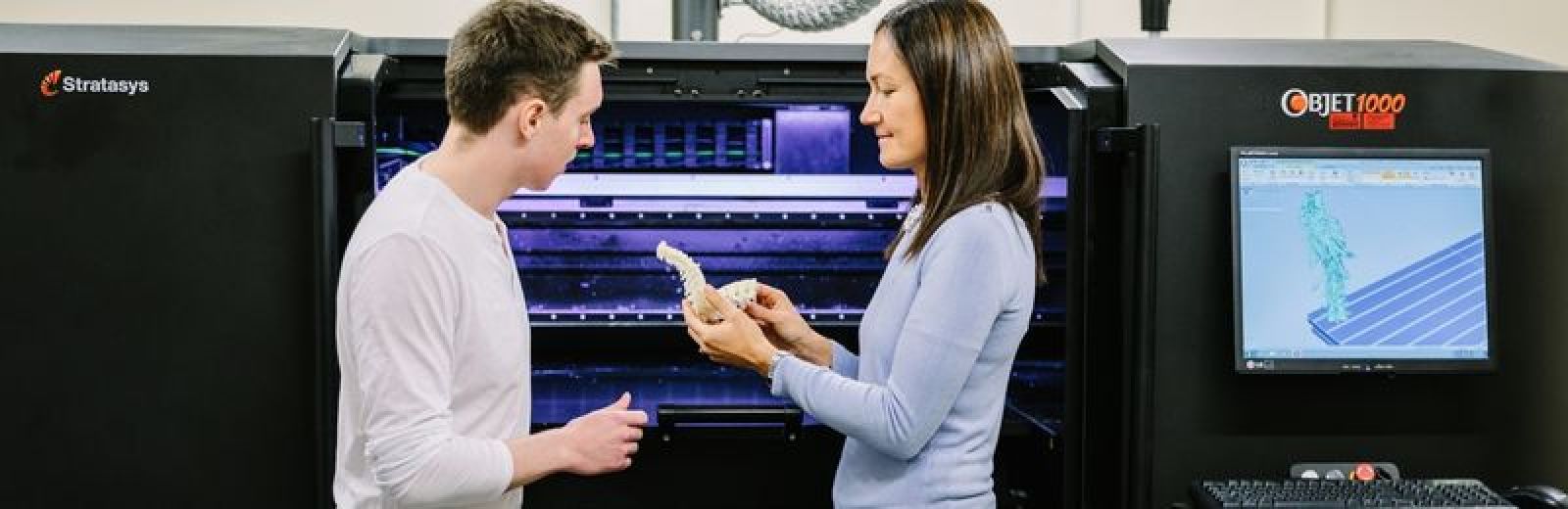 An academic showing a student a 3d printed model in a electronics lab.
