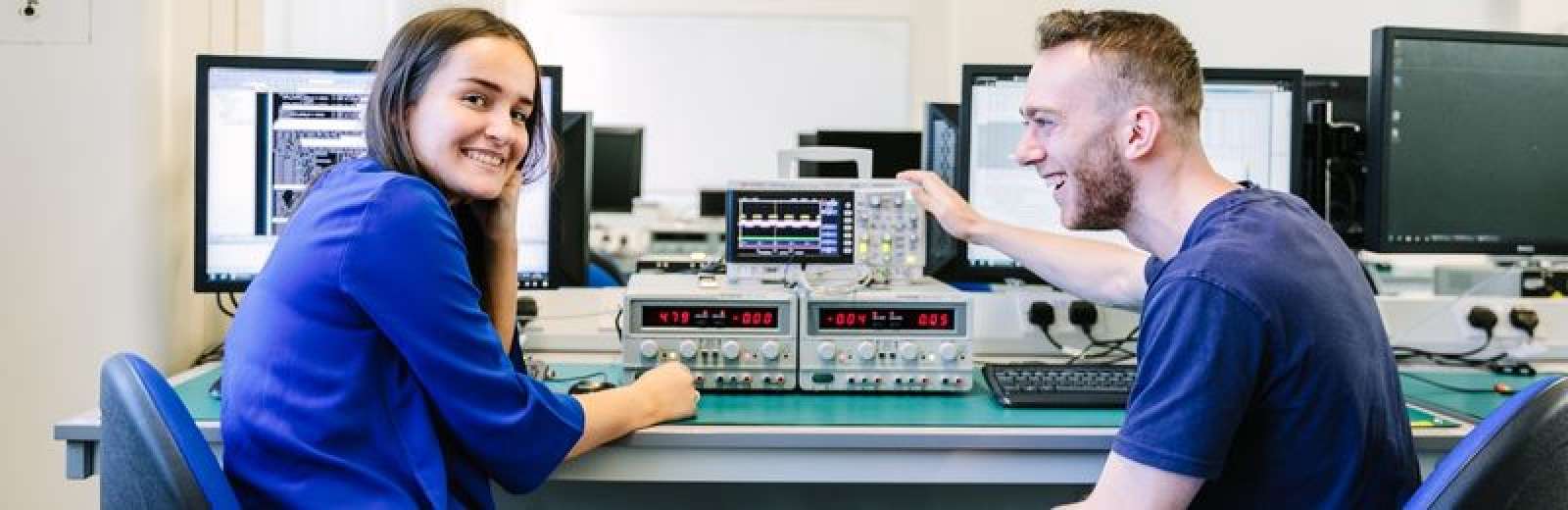 Two students sat a workbench in a lab in the School of Electronic and Electrical Engineering.