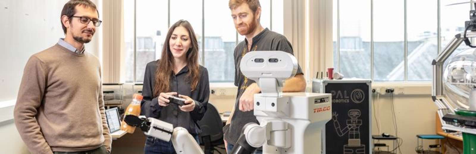 Three students working with a robot in a lab at the University of Leeds.